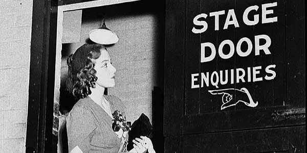 Entertainer reads the "Stage door enquiries" sign in a JCW theatre, Sydney, 1938 © Sam Hood - State Library of New South Wales
