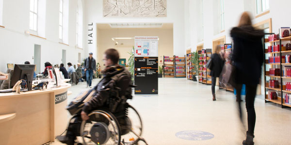 Un étudiant en fauteuil à l'accueil de la BU Droit-Eco-Gestion de l'Université de Rennes 1